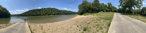a panoramic view of a lake surrounded by trees and grass