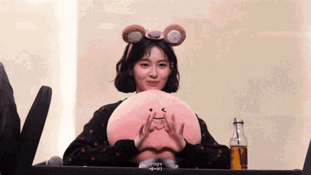 a woman wearing a headband holds a stuffed animal in her hands
