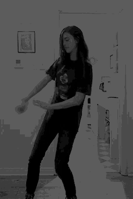 a woman in a black t-shirt with mickey mouse on it is standing in a hallway