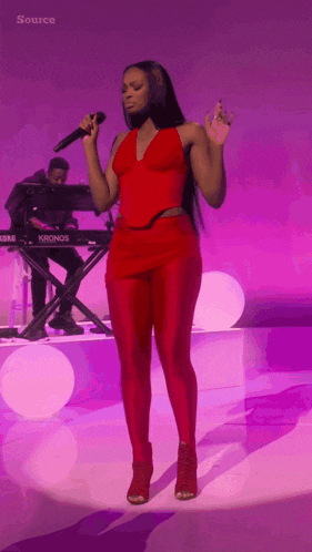 a woman singing into a microphone in front of a keyboard that says kronos on it