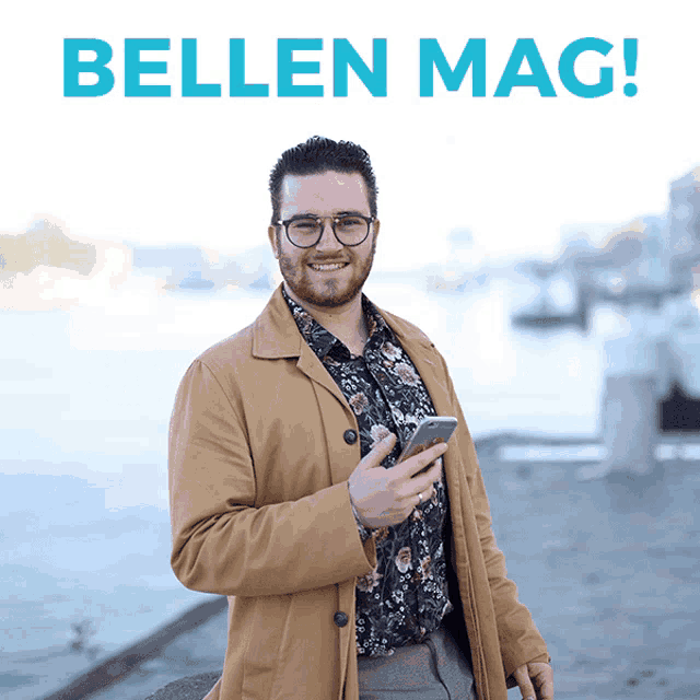 a man wearing glasses holds a cell phone in front of a sign that says bellen mag