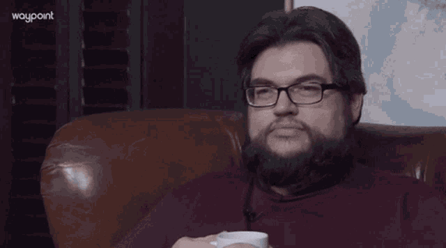 a man with glasses and a beard is drinking from a mug that says zeit