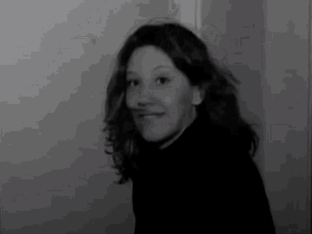 a black and white photo of a woman with long hair smiling .