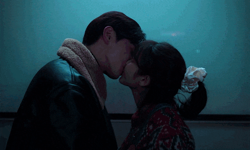 a man and a woman kissing in front of a white board