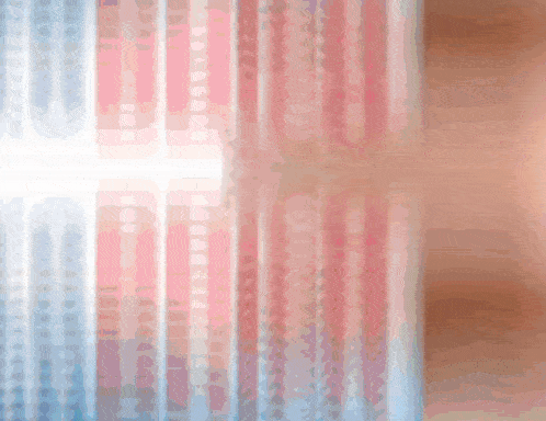 a blurred image of a window with a pink and blue curtain