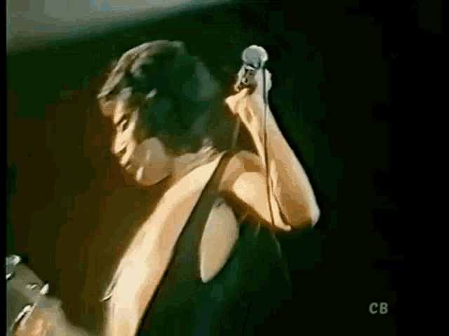 a man is singing into a microphone while standing on a stage .