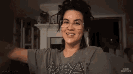 a woman wearing glasses and a nasa shirt flexes her muscles