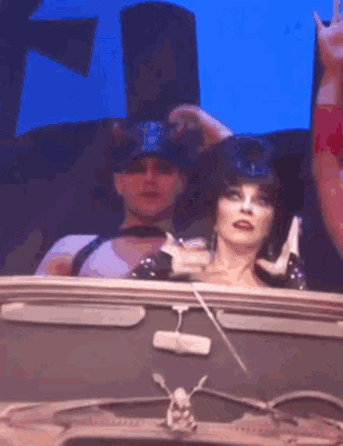 a man and a woman are sitting in a car on a stage