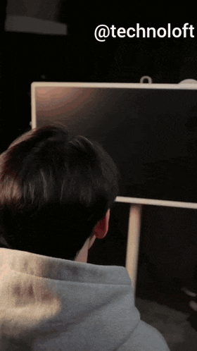a man in a blue hoodie is looking at a screen with the words @technoloft written above him