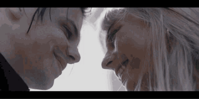 a man and a woman are looking into each other 's eyes and smiling
