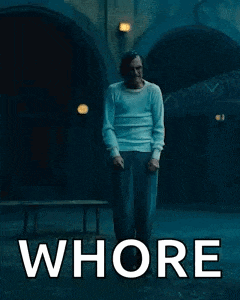 a man in a white shirt is standing in front of a building with the words `` whore '' written on the poster .
