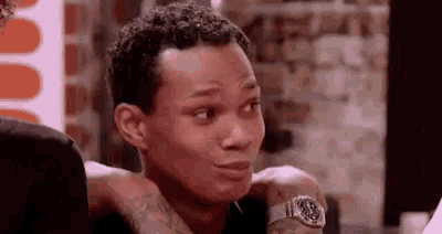 a man wearing a watch is making a funny face while talking to another man .
