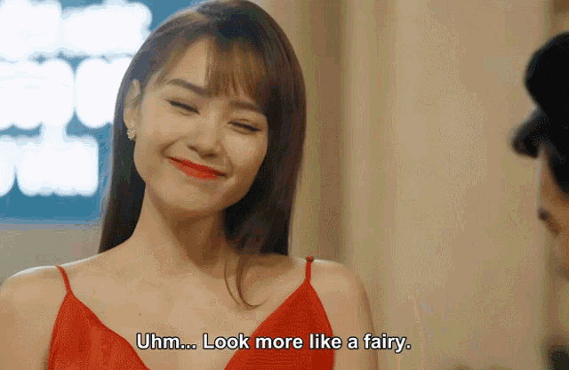 a woman in a red dress smiles and says uhm look more like a fairy