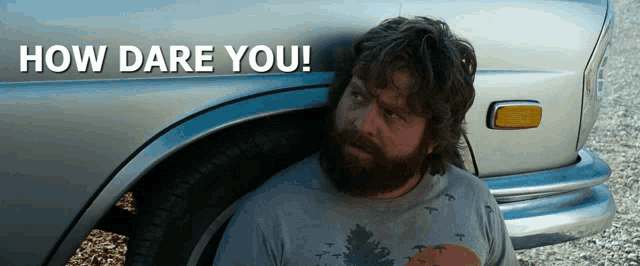 a man with a beard is standing in front of a car with the words how dare you