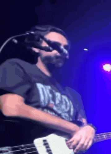 a man playing a guitar with a shirt that says detroit on it