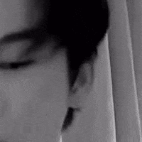 a black and white photo of a man 's face looking at himself in a mirror .
