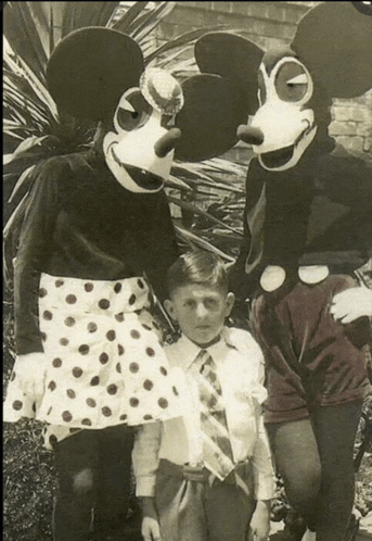 a black and white photo of mickey mouse and minnie mouse posing with a young boy