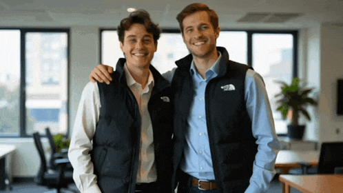 two men wearing vests that say the north face are posing for a picture