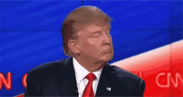 donald trump is making a funny face while giving a speech .