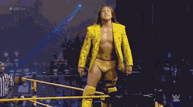 a wrestler in a yellow suit is standing in the ring
