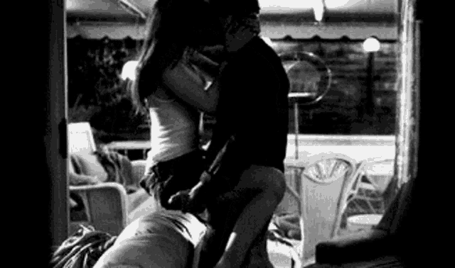 a black and white photo of a man and woman kissing .