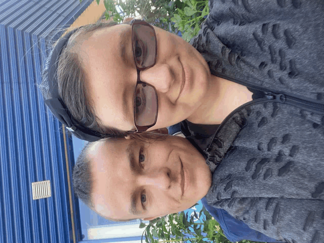 a man and a woman are posing for a picture and the woman is wearing sunglasses
