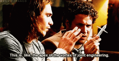 two men are looking at a model airplane and one of them is saying this is like the apex of the vortex of joint engineering .