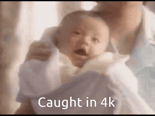 a baby is being held in a woman 's arms with the caption " caught in 4k "