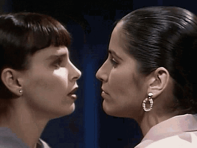 two women are looking at each other with their eyes closed .