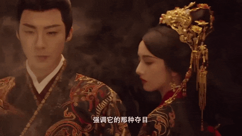 a man and a woman are standing next to each other in a dark room with chinese writing in the background