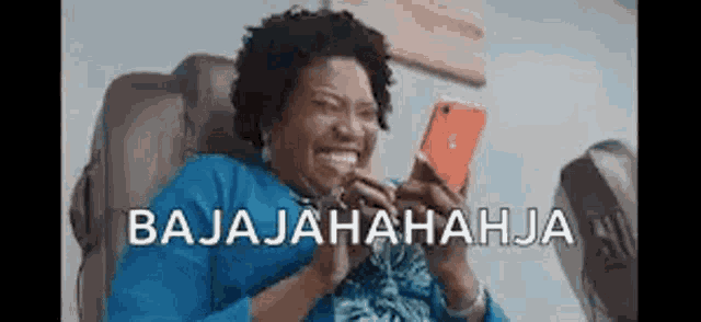 a woman is sitting in a chair laughing while looking at a cell phone .