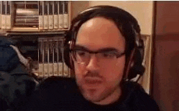 a bald man wearing glasses and headphones is sitting in front of a computer .