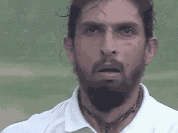 a close up of a man with a beard wearing a white shirt and a necklace .