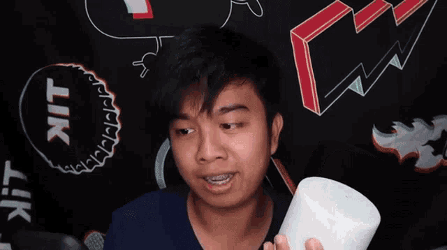 a man is holding a white object in front of a black background with lik written on it