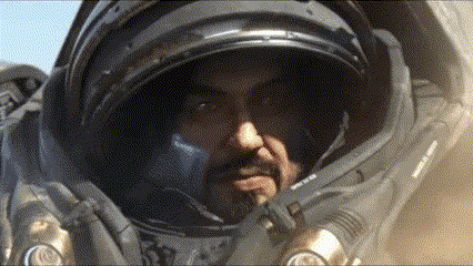 a man in a space suit looks at the camera with his hand on his chin