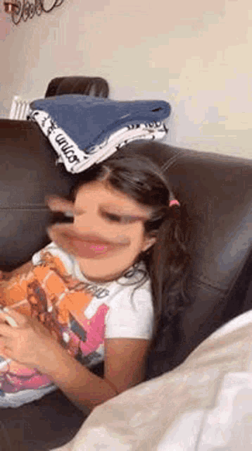 a little girl is sitting on a couch with her mouth open and making a funny face .