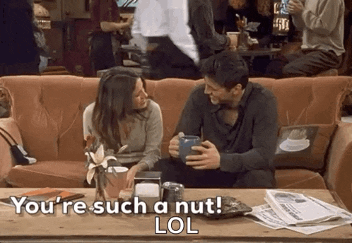 a man and a woman are sitting on a couch talking to each other while holding cups of coffee .