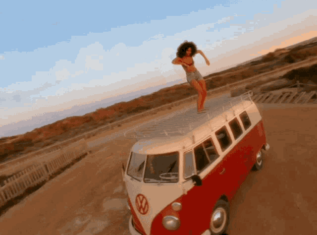 a woman in a bikini stands on top of a vw van