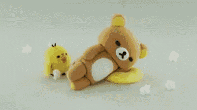 a teddy bear and a chicken are laying on a white surface .