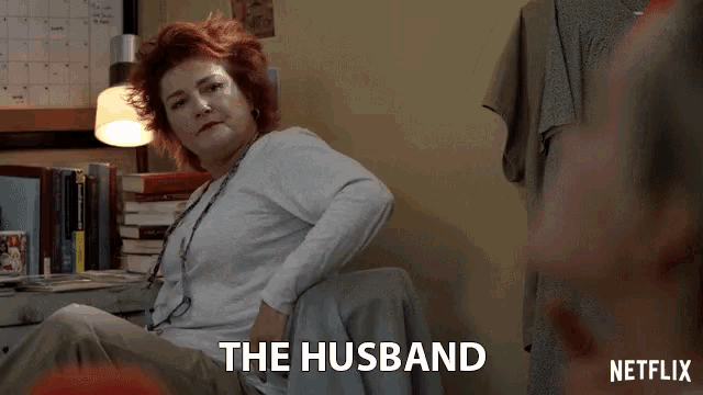 a woman sits in a chair with the words " the husband " on the bottom right