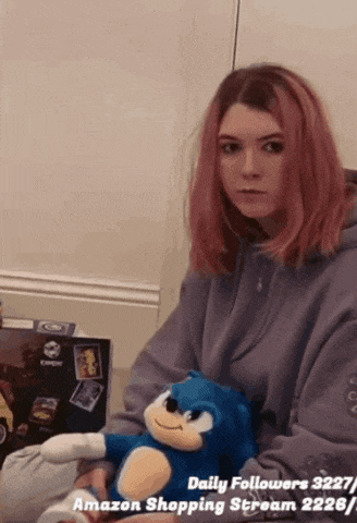 a girl with pink hair is holding a blue stuffed sonic