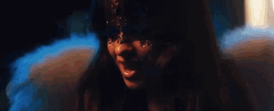 a close up of a woman 's face in a dark room with smoke coming out of her eyes .