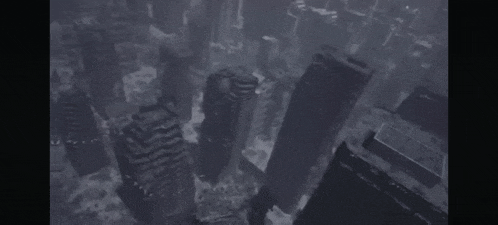 an aerial view of a city with a lot of buildings and clouds coming out of it .