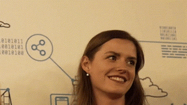 a woman is smiling in front of a wall with drawings of clouds and numbers