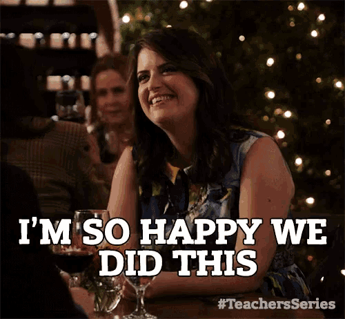 a woman is smiling while sitting at a table with a glass of wine and says i 'm so happy we did this