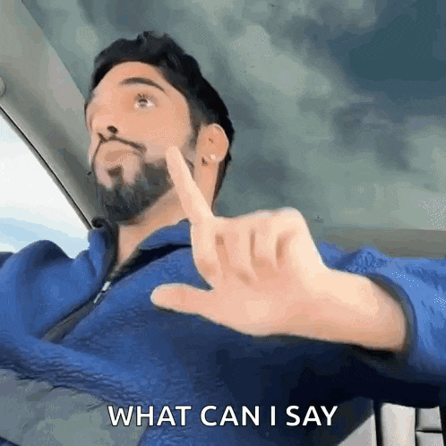 a man with a beard is driving a car and making a hand gesture with his finger .