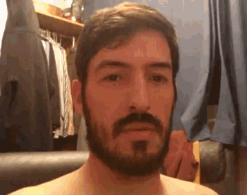a shirtless man with a beard and mustache is looking at the camera