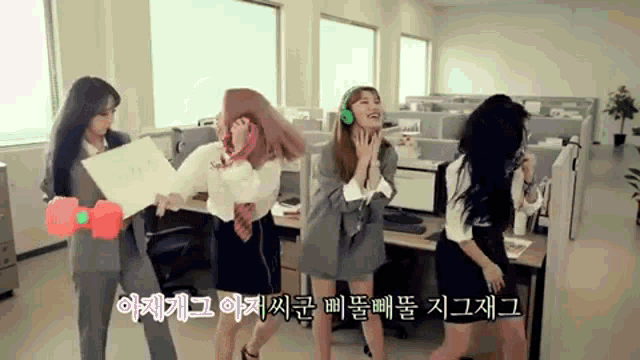 a group of women are dancing in an office cubicle while wearing headphones .