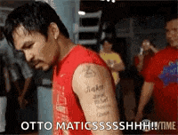 a man with a tattoo on his arm is standing in front of a crowd of people .