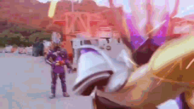 a blurry picture of a man in a purple and gold costume standing in front of a roller coaster .